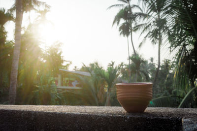 Coffee cup in evening sunlight on roof beam of a residential building with bokeh background.