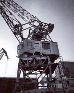 Low angle view of crane at construction site against sky