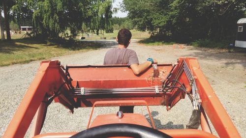 Rear view of man standing by tractor at field