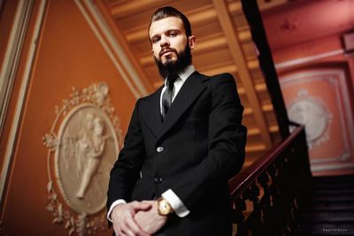 Portrait of man in suit standing on steps at home