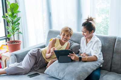 Young woman using smart phone while sitting on laptop