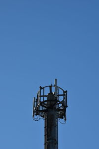 Low angle view of communications tower against clear blue sky