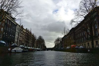 Canal amidst city against sky