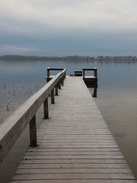 Wooden jetty on pier over lake against sky