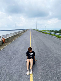 Rear view of man standing on road against sky