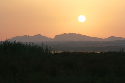 Grass with lake and silhouetted mountains a dusk