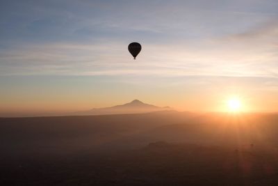 Hot air balloons flying against sky during sunset with a mountain in the background