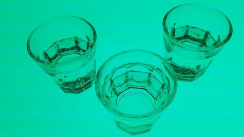 Close-up of water in drinking glasses against green background