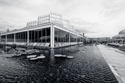 Modern building by pond against sky