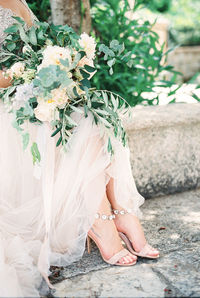 Low section of bride holding bouquet