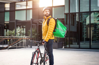 Man standing with bicycle on street in city