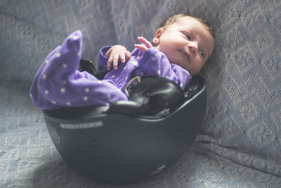 Close-up of baby resting in helmet on sofa