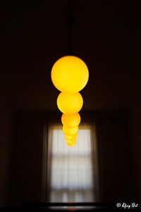Low angle view of illuminated light bulb hanging from ceiling