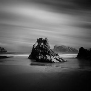 Rock formation in sea against sky