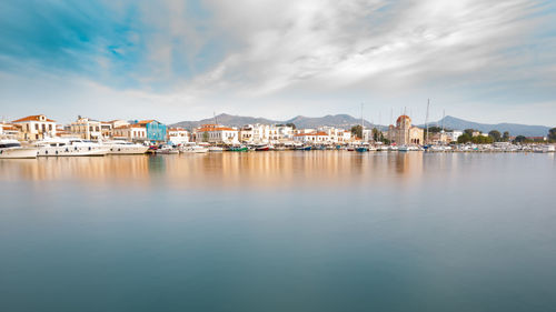 View of city at waterfront against cloudy sky