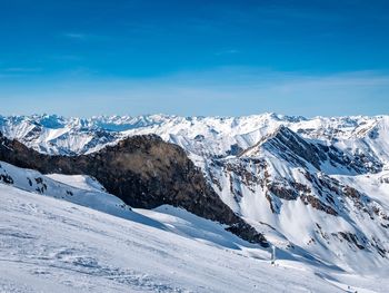 Scenic view of snowcapped mountains against blue sky