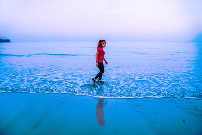 Side view of woman on beach against sky