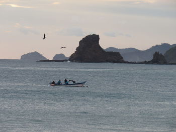 People on boat in sea against sky