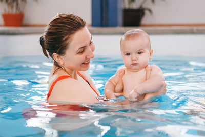 Woman holding baby boy in swimming pool