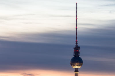 Fernsehturm against cloudy sky during sunset