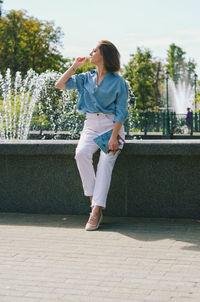 Portrait of young elegant business woman in eye glasses walking in city street with phone. urban