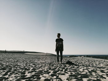 Man standing on beach against clear sky