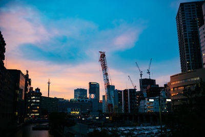 Modern buildings in city against sky during sunset