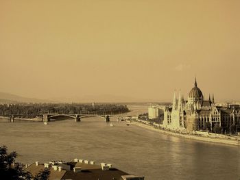 Bridge over river in city against sky