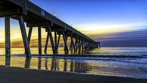 Pier over sea against sky during sunset