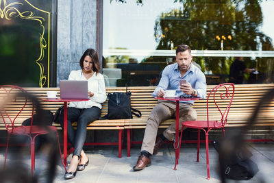 Business people using laptop and smart phone at sidewalk cafe