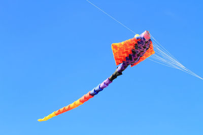 Low angle view of stingray shape kite flying in clear blue sky