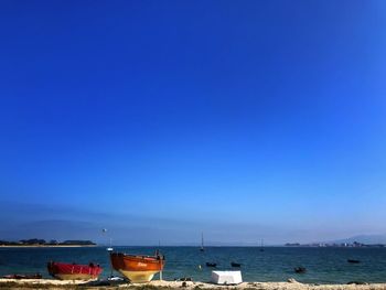 Sailboats moored on sea against clear blue sky