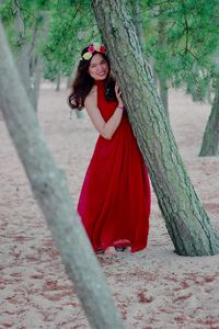 Portrait of woman standing by tree trunk