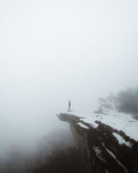 Man on snow covered land against sky