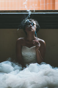 Close-up of young woman sitting on bed