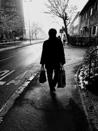 Rear view of man walking on street in city