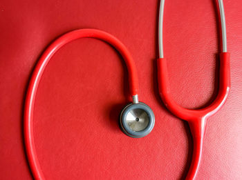 High angle view of stethoscope against red table