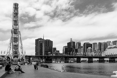 City at waterfront against cloudy sky