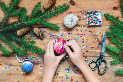 Cropped hands of woman making christmas decoration on table