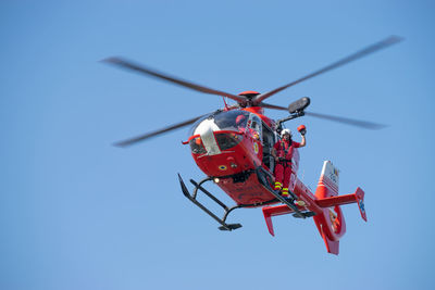 Low angle view of helicopter flying against clear blue sky