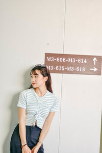 Young woman standing against wall indoors