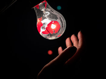 Close-up of hand holding glass against black background