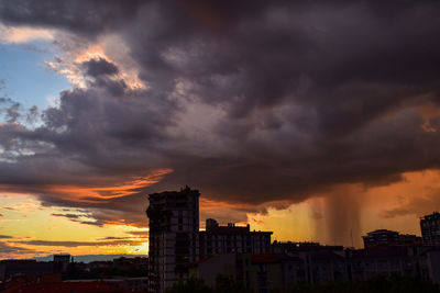 Buildings against dramatic sky during sunset