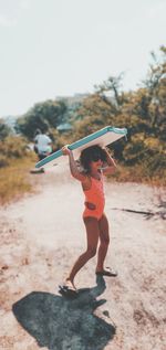 Full length of woman with arms raised standing on land