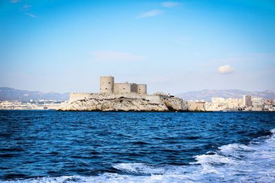 Buildings by sea against sky