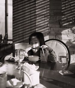 Cropped hand feeding girl sitting at table