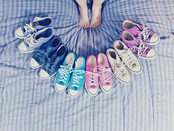 Low section of woman by colorful shoes arranged on bed