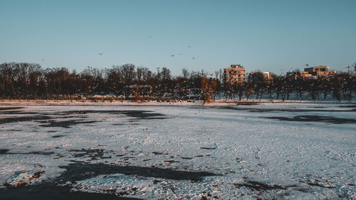 Snow covered city buildings against clear sky