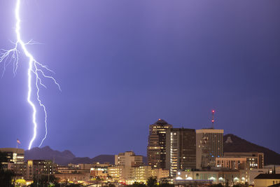 Lightning over illuminated buildings in city at night