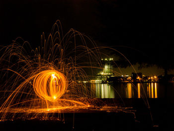Wire wool at lakeshore against sky at night